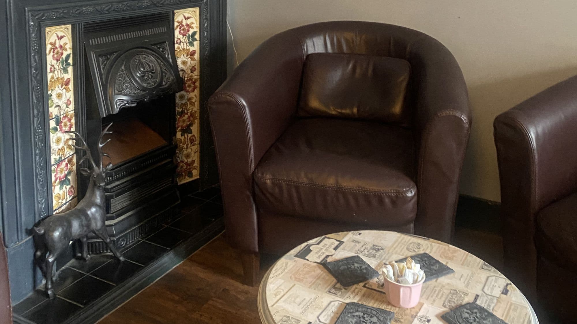 Ornate fireplace and leather chairs in the cosy back room at Grace & Flavour Tea Emporium in Rochester.