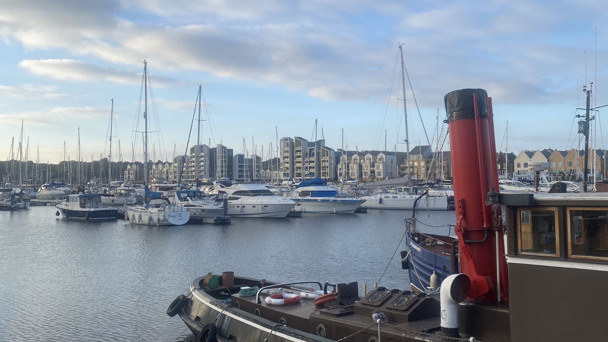 Boats moored on the River Medway at Chatham marina with waterside buildings in the background