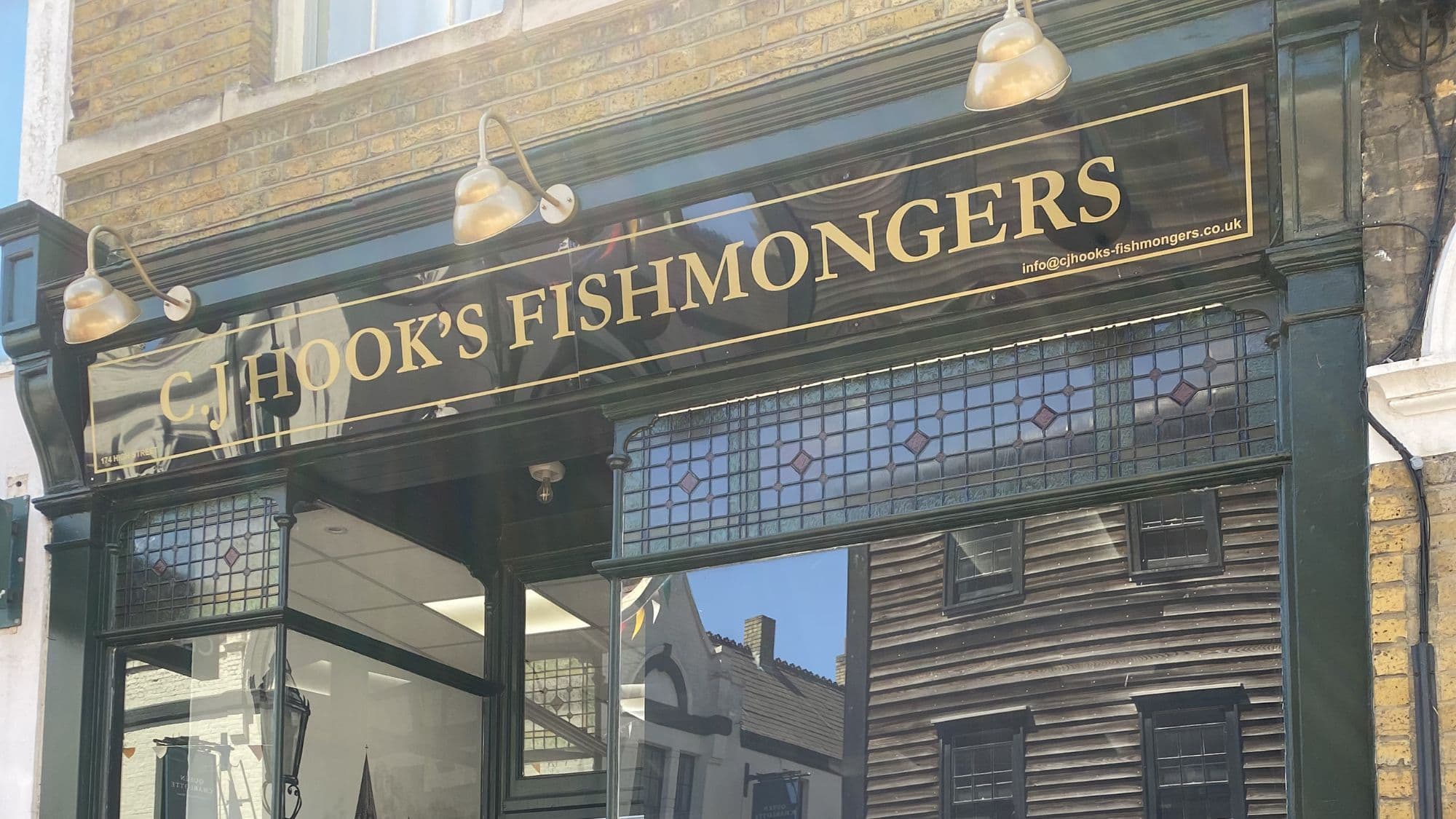 The restored frontage of C J Hook's Fishmongers on Rochester High Street with traditional gold signage, stained-glass windows and racing green woodwork.