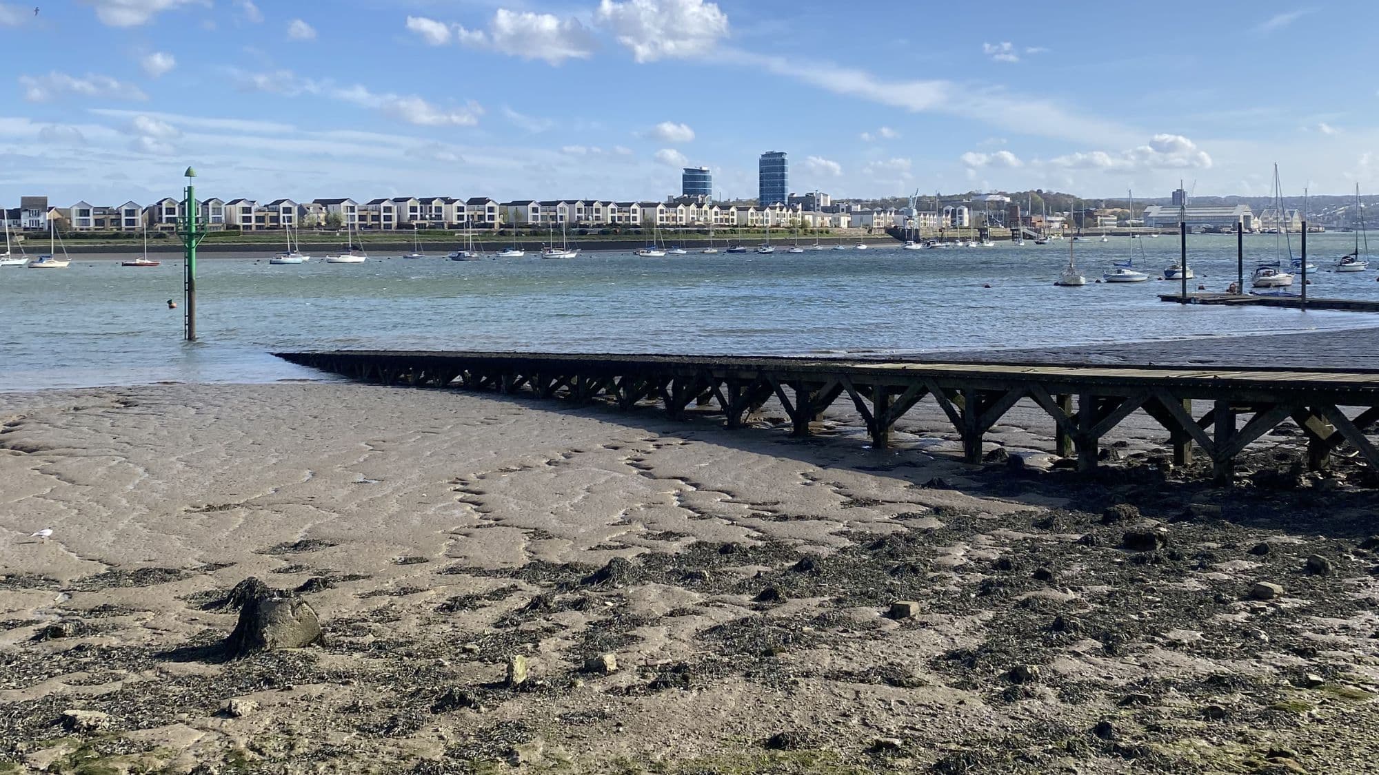 Wooden jetty extending across the tidal shoreline at Upnor beside the River Medway estuary.