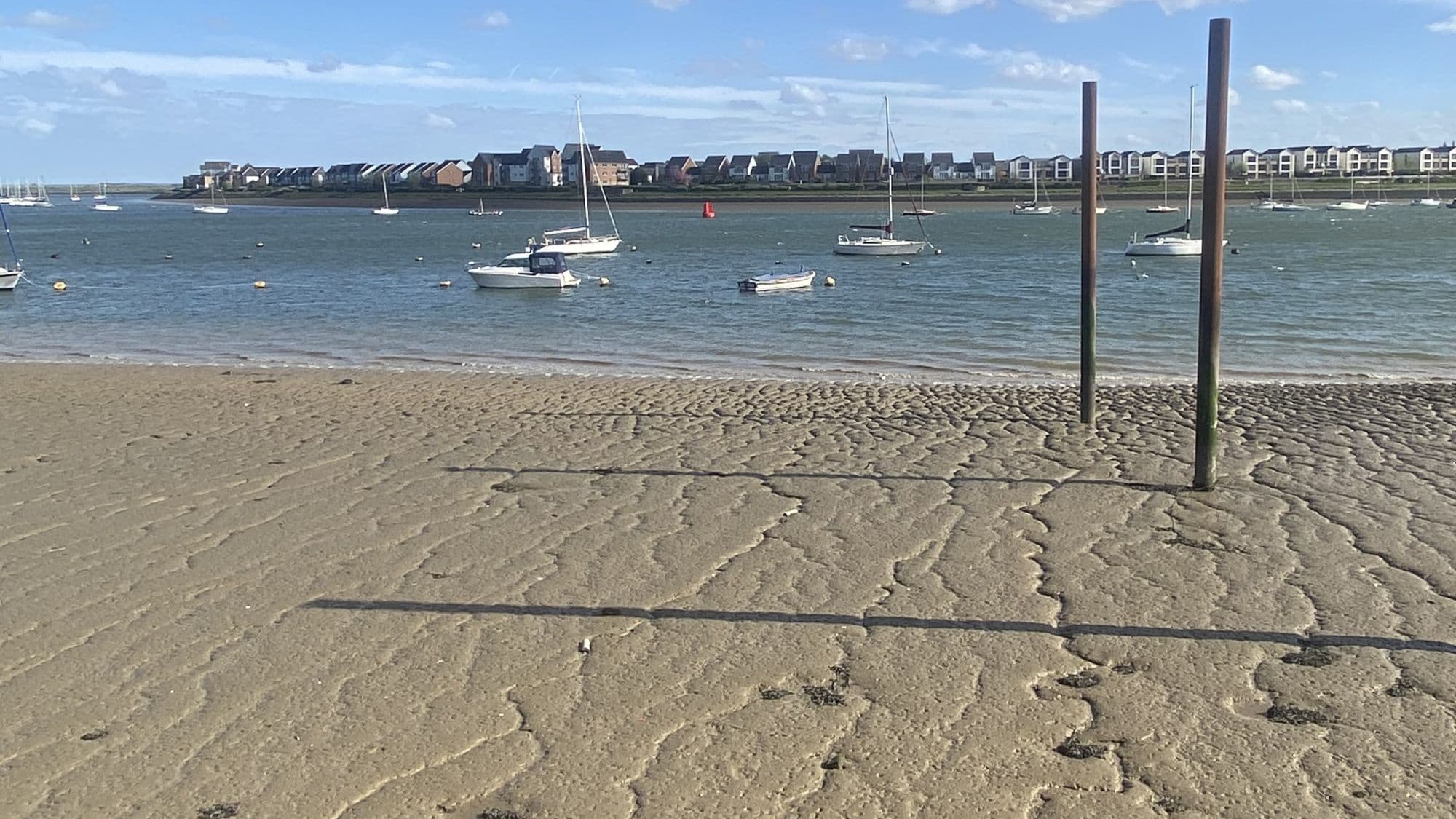 Tidal sand, sailing boats and the River Medway at Upnor as the estuary begins to open towards the Thames.